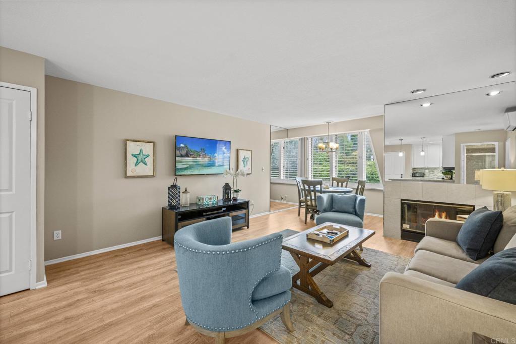 Living room with lit fireplace, blue tufted ottoman, and beach-inspired art.