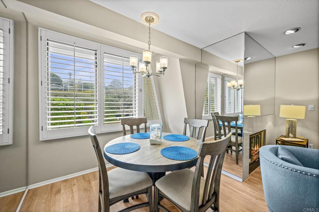 Dining nook with plantation shutters, mirrored wall, and fireplace beyond.