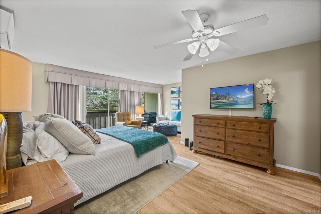Primary bedroom with sliding glass door to private balcony over greenery.