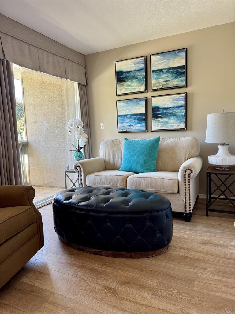 Reading nook with coastal art and tufted leather ottoman.