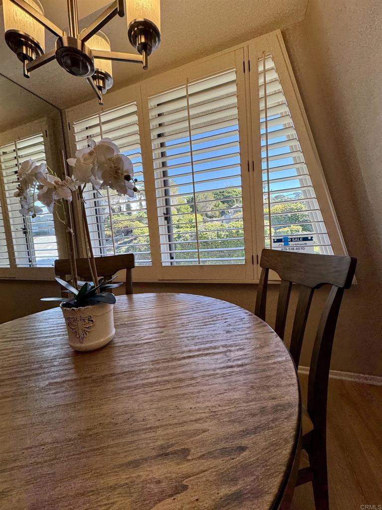 Dining nook overlooking village trees through plantation shutters.