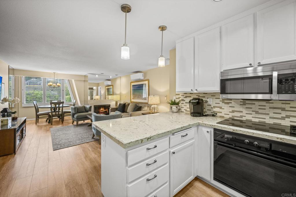 Open-concept living room with lit fireplace, beach-inspired interior, and morning light at 1562 Camino Del Mar #643.